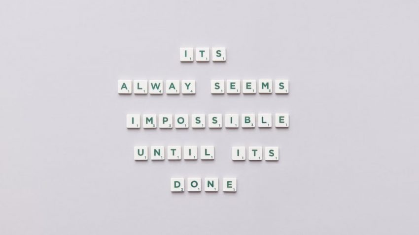 Motivational quote 'It always seems impossible until it's done' in Scrabble tiles.